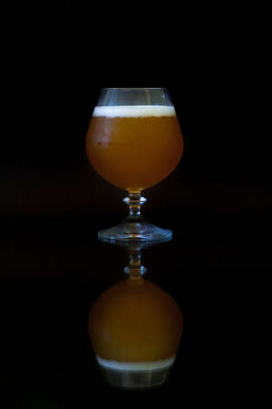 Misted glass of beer on the leg with reflection on black background.の写真素材