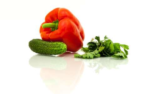 Fresh green cucumber, red bell pepper and fresh parsley with reflection on white background.の写真素材