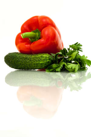 Fresh green cucumber, red bell pepper and fresh parsley with reflection on white background.の写真素材