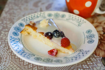 Piece of sweet cake with berries and cream sauce on a plate on a rustic kitchen.の写真素材