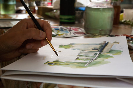 Hand with a brush paints a watercolor workshop.の写真素材