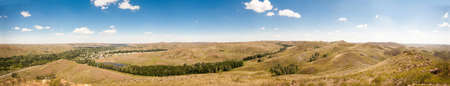 Summer panorama of the hilly terrain of the steppe lake, trees and village.の写真素材