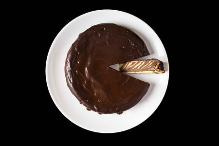 Chocolate cake drizzled with chocolate icing on a black isolated background. Flat lay. Homemade baking.の写真素材