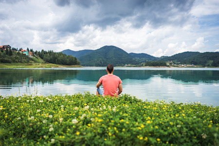 One man sits alone and meditates in the nature looking forward on Zaovine lake in Serbia, relax and feel freedomの写真素材