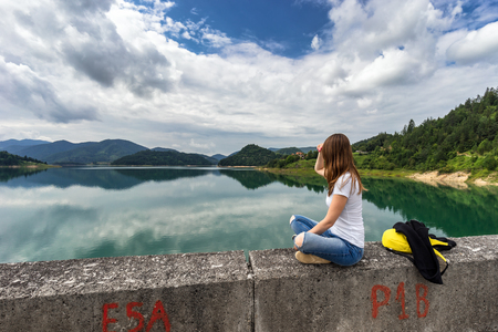 Young woman sitting and looking on Zaovine lake in Serbiaの写真素材