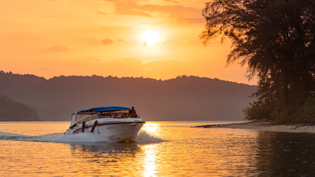 Nopparat Thara, Krabi Province, Thailand - January 14, 2019: Modern speedboat floats in the water at the orange sunsetのeditorial素材