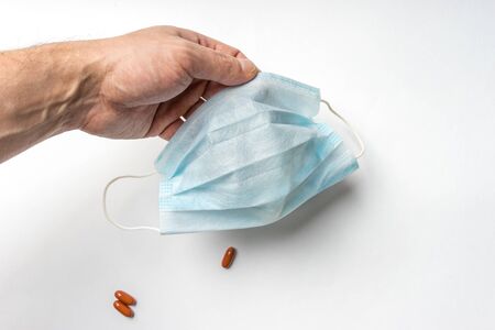 Medical protective mask from virus and infections in a man's hand. Close-up view on a white background with space for textの写真素材
