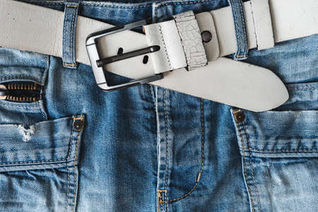 Blue casual jeans with white belt and pockets. Detail flat lay close-up view from above. Textured natural backgroundの写真素材