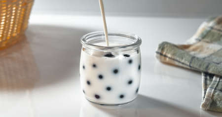 Milk is poured into a jar with fresh berries. Preparation of natural homemade yogurt in the morning for breakfastの写真素材