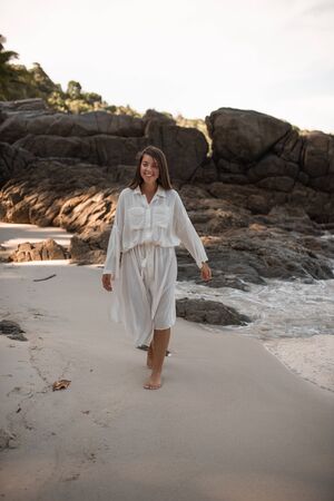 european young tan women have rest and run on white sand beach. long black chestnut hair . white cotton clothes. boho style dress.Thailand. Aquamarine crystal seaの写真素材