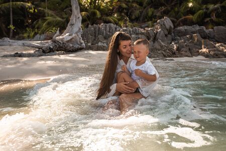 Happy smile european family have rest and run on white sand beach. Father, long black chestnut hair mother, blond baby boy. white cotton clothes. boho dress. t-shorts.Thailand. Aquamarine crystal seaの写真素材