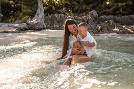 Happy smile european family have rest and run on white sand beach. Father, long black chestnut hair mother, blond baby boy. white cotton clothes. boho dress. t-shorts.Thailand. Aquamarine crystal seaの写真素材