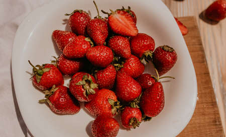 scattered juicy fresh red strawberries on the table with vintage plank. mint leaf. drops and splashes of spilled milk. vegetable cutting board. High quality photoの写真素材