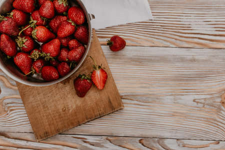 scattered juicy fresh red strawberries on the table with vintage plank. mint leaf. drops and splashes of spilled milk. vegetable cutting board. High quality photoの写真素材