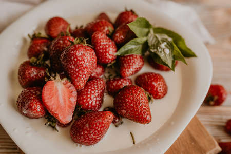 scattered juicy fresh red strawberries on the table with vintage plank. mint leaf. drops and splashes of spilled milk. vegetable cutting board. High quality photoの写真素材