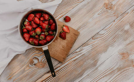 scattered juicy fresh red strawberries on the table with vintage plank. mint leaf. drops and splashes of spilled milk. vegetable cutting board. High quality photoの写真素材