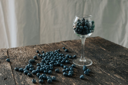 Fresh blue matte round blueberries filled in a transparent glass stands on a wooden brown shabby...