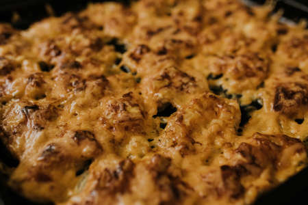 Meat cheese pizza. Baked meat in the oven lies on a black metal baking sheet. mouth-watering cheese sauce.の写真素材