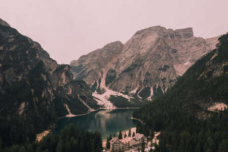 A large clear azure aquamarine green lake with brown wooden boats. High snow-capped stone mountains. Aerial top view from drone.の写真素材
