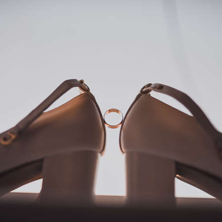 a ring between two womens high heel shoes. Morning of the brideの写真素材