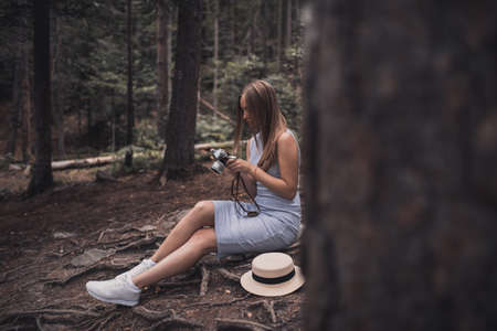 Slavic tanned fair-haired young girl with a boater hat on nature. Traveler tourist in a dark forest. constant tone of clothes. dark brown backgroundの写真素材