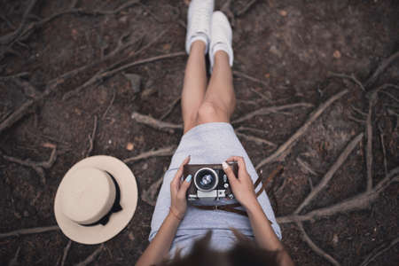 Slavic tanned fair-haired young girl with a boater hat on nature. Traveler tourist in a dark forest. constant tone of clothes. dark brown backgroundの写真素材