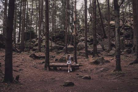 Slavic tanned fair-haired young girl with a boater hat on nature. Traveler tourist in a dark forest. constant tone of clothes. dark brown backgroundの写真素材