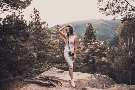 Slavic tanned fair-haired young girl with a boater hat on nature. Traveler tourist in a dark forest. constant tone of clothes. dark brown backgroundの写真素材