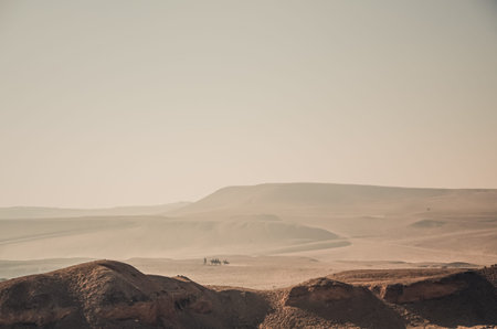Endless yellow sandy hot desert. Lonely Egyptians on camels are walking in the distance.の写真素材