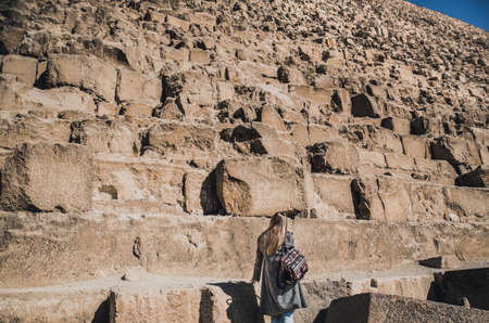 A European blonde walks near the pyramids in the desert in Cairo. The girl against the background of ancient buildings in Giza. Egyptian Sphinxの写真素材
