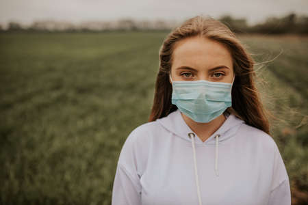 Young blond European woman in a protective mask outdoors.の写真素材