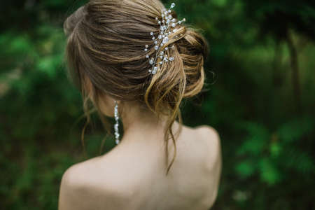 women greek style hairstyle for long hair careless bun with decoration, jewelry, photo from the backの写真素材