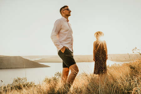 woman behind man in rays of setting sun in summer near lakeの写真素材