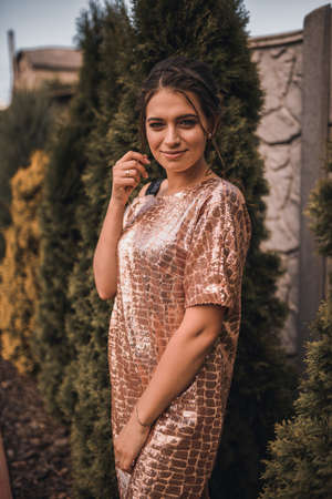 young tanned woman in shiny crocodile print dress. Easy messy hairstyle on long black hair.の写真素材