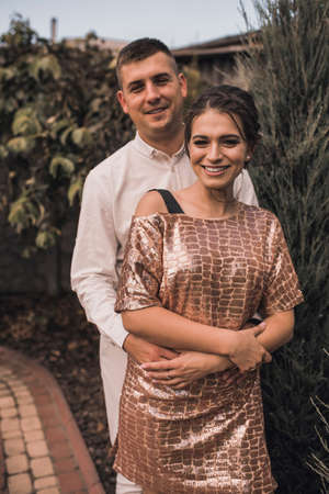 Young couple of lovers man and woman in festive fashionable clothes are hugging. Light casual hairstyle for women with a perm. Summer nature outside background.の写真素材