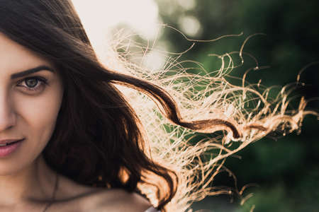 Portrait of a curly-haired bride in a wedding dress in the rays of the sunの写真素材
