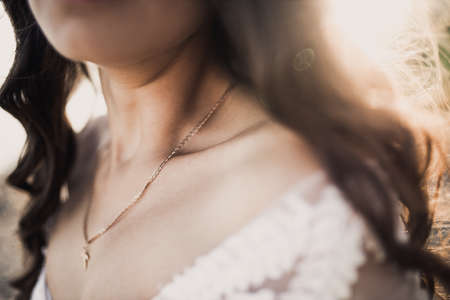 female clavicle tanned girl. Curly-haired bride in a wedding dress in the rays of the sun.の写真素材