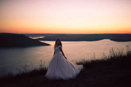 Silhouette of bride in a wedding dress at night against backdrop of a large lake and islands. Bakota, Ukraineの写真素材