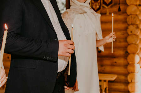Woman and man hands hold lighted candles in the church. godfather and godmatherの写真素材