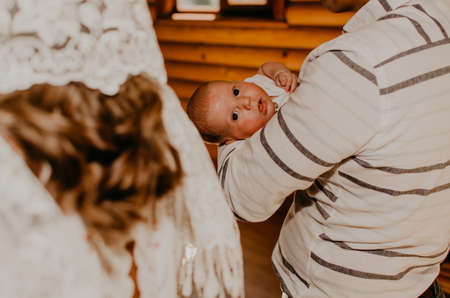 baby hand in arms of godfather. rite of sacrament of epiphany in churchの写真素材
