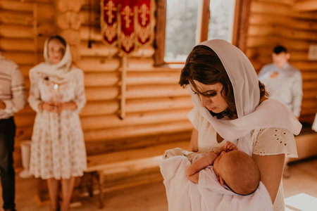 rite of sacrament of epiphany child baby in church. A mother is holding a newborn child in her arms.