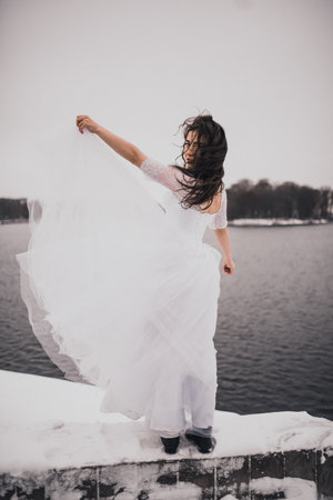 girl brunette bride in a wedding dress in winter my in snow. bridal look style fashion 2021の写真素材