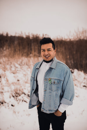 Hispanic brunette man with beard in denim jacket in winter in the middle of snow. Men's Street Fashion Casual Style 2021の写真素材