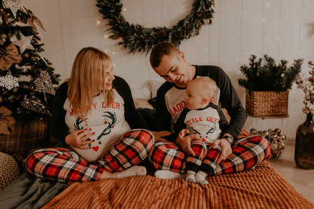 cheerful happy family in pajamas with child lie on the bed in the bedroom. new year family clothes looks outfits. Valentine's Day Celebration Giftsの写真素材