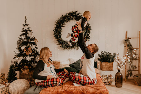 cheerful happy family in pajamas with a child kissing on the bed in the bedroom. new year family clothes looks outfits. Valentine's Day Celebration Giftsの写真素材