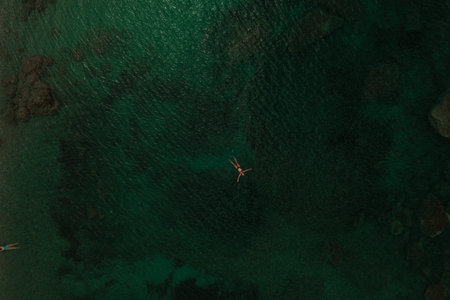 Aerial top nature view above green turquoise Adriatic sea in Albania. Beautiful young woman swimming...