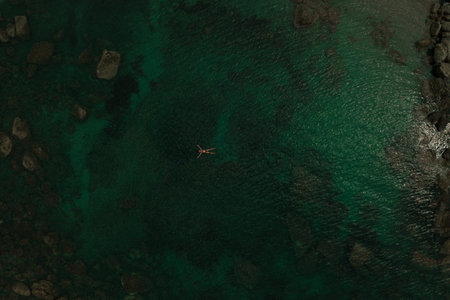 Aerial top nature view above green turquoise Adriatic sea in Albania. Beautiful young woman swimming...