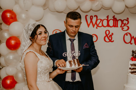 groom and bride at wedding cut their large multi-tiered white cake taste it fed from each other....