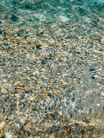 Close up sea waves stones shells beach summer day. top view above transparent water. Ocean clear sea. Summer background nature. Stones under water. Texture wallpaper background free space for textの写真素材