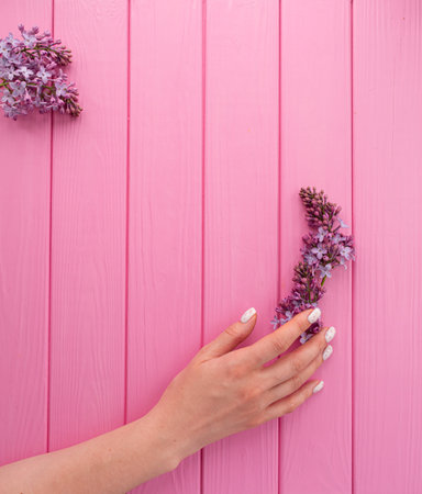 Summer abstract background mockup template free copy space for text pattern sample top view above pink wooden board. blank empty area for inscription. woman hand manicure hold blossom flowers lilacの写真素材